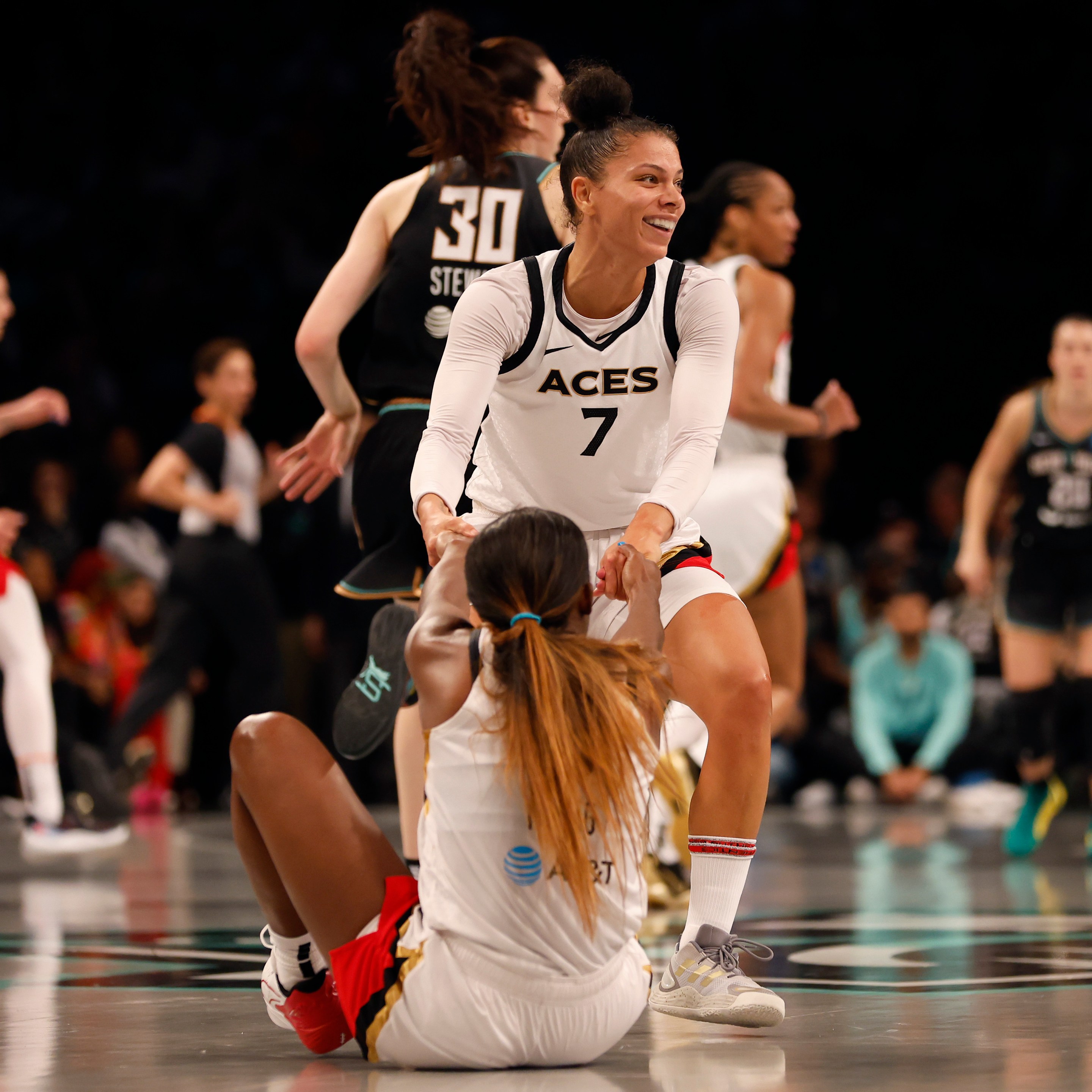 Alysha Clark #7 of the Las Vegas Aces helps teammate Jackie Young #0 up off the court in the second quater against the New York Liberty during Game Four of the 2023 WNBA Finals at Barclays Center on October 18, 2023 in New York City.