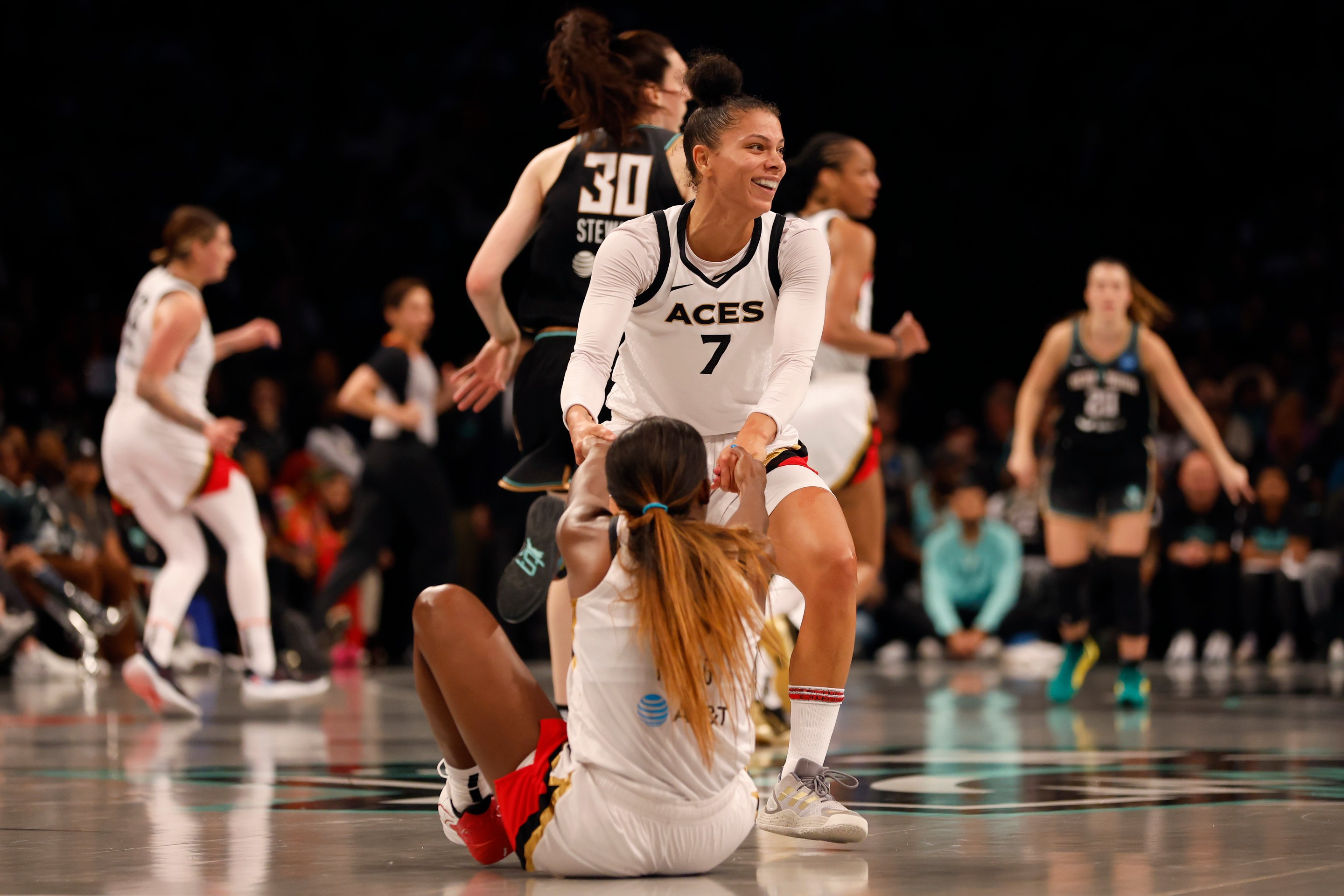 Alysha Clark #7 of the Las Vegas Aces helps teammate Jackie Young #0 up off the court in the second quater against the New York Liberty during Game Four of the 2023 WNBA Finals at Barclays Center on October 18, 2023 in New York City.