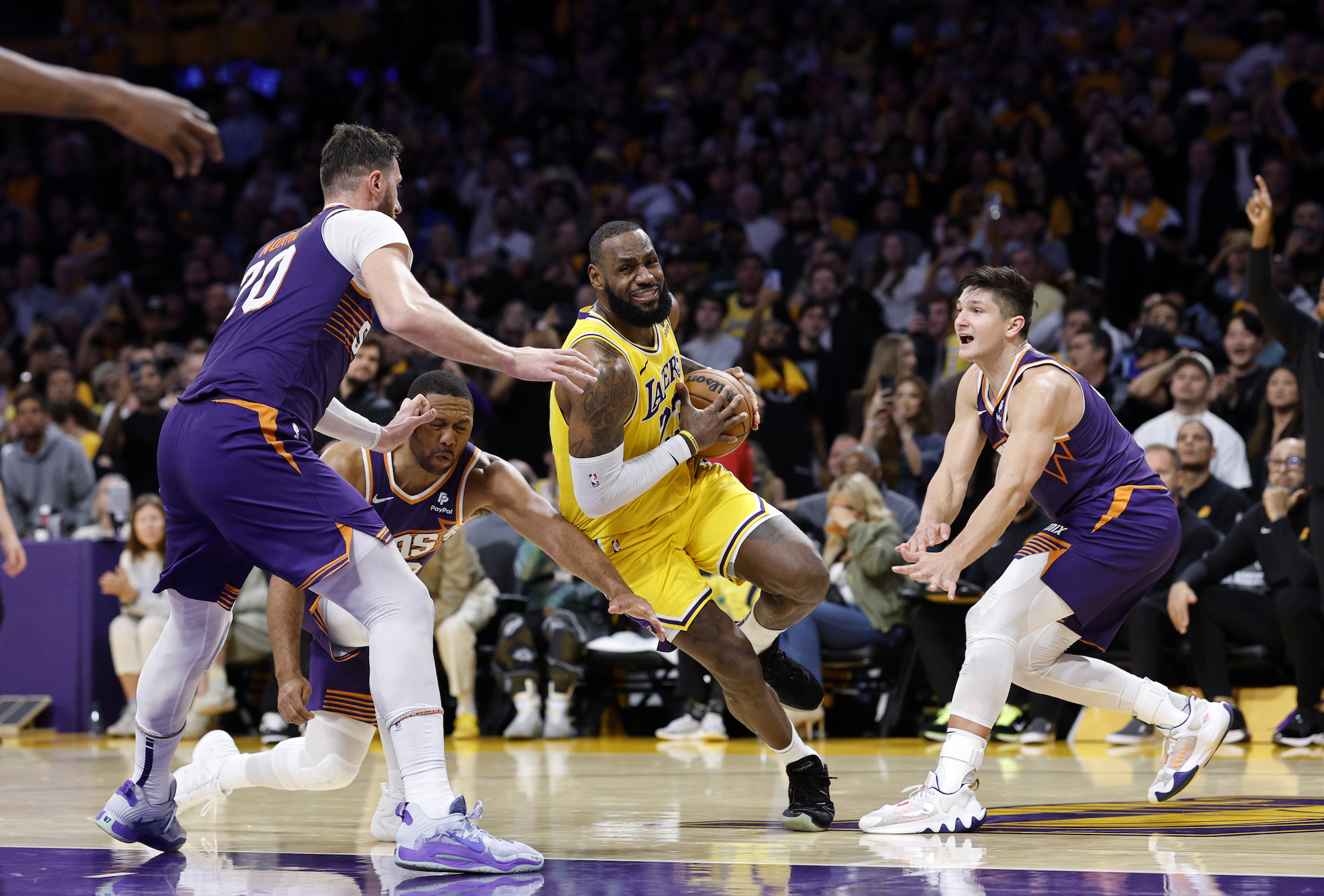 LeBron James powers through three Suns defenders in the fourth quarter of Thursday's game.