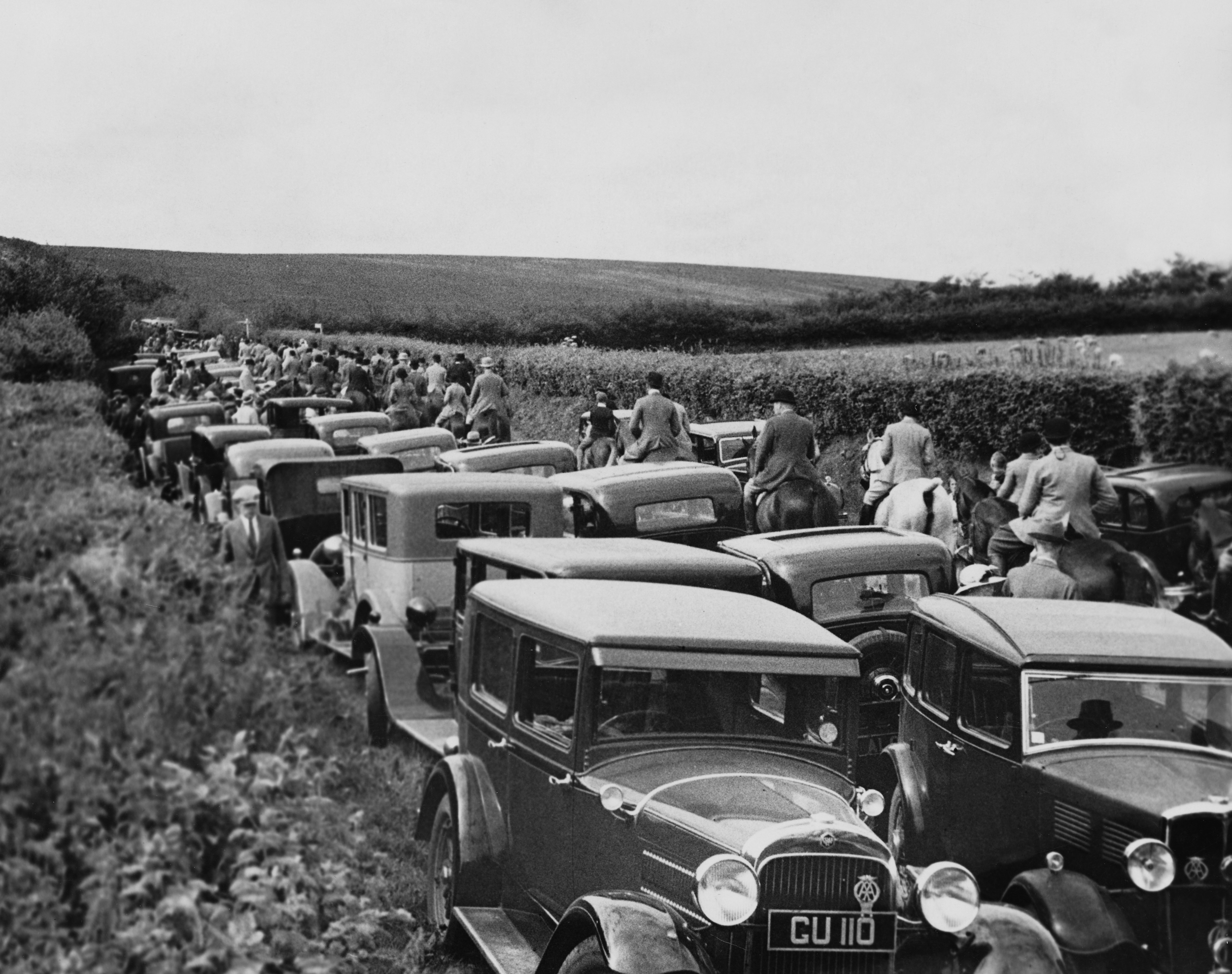 Cars and horseback riders share a packed country road in 1935.