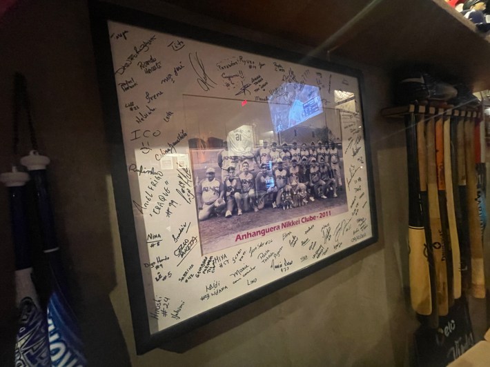 An autographed team photo of the Anhanguera Nikkei Baseball Club from 2011, on display at Pitchers Burger and Baseball in São Paulo.