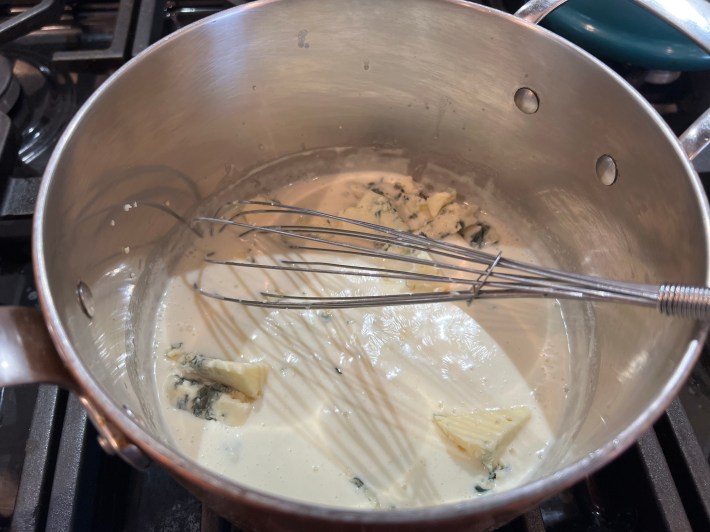 Roquefort and gorgonzola melt in simmering cream in a saucepan.