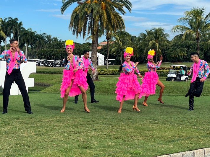 Pink-clad dancers perform in front of the large "LIV GOLF" sign near the entrance.
