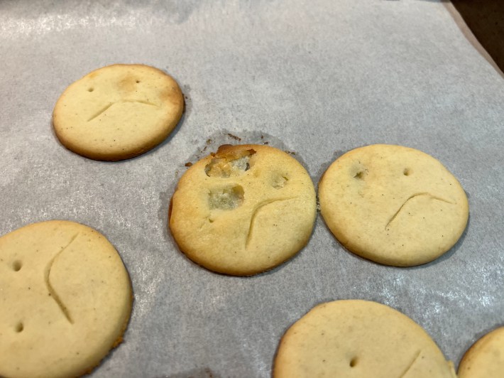 One of the frowning cookies has melted right through the forehead, due to a pocket of unmixed butter melting out the bottom.