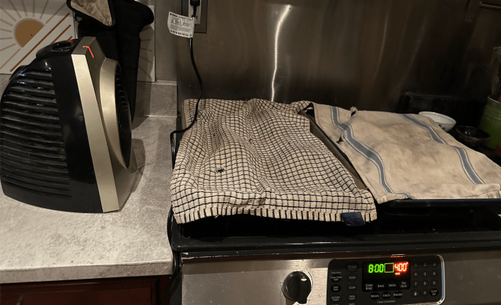 space heater pointed at two cookie sheets covered in dish towels.