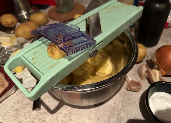 A mandolin on top of a bowl on a messy counter