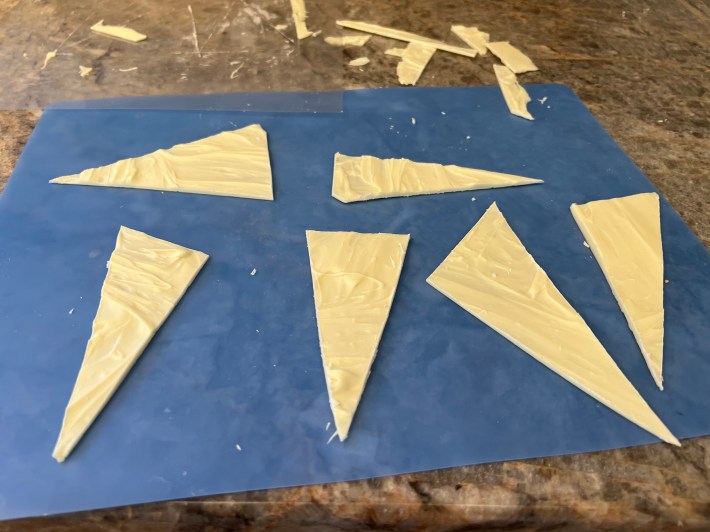 Six long thin triangles cut out of tempered white chocolate.