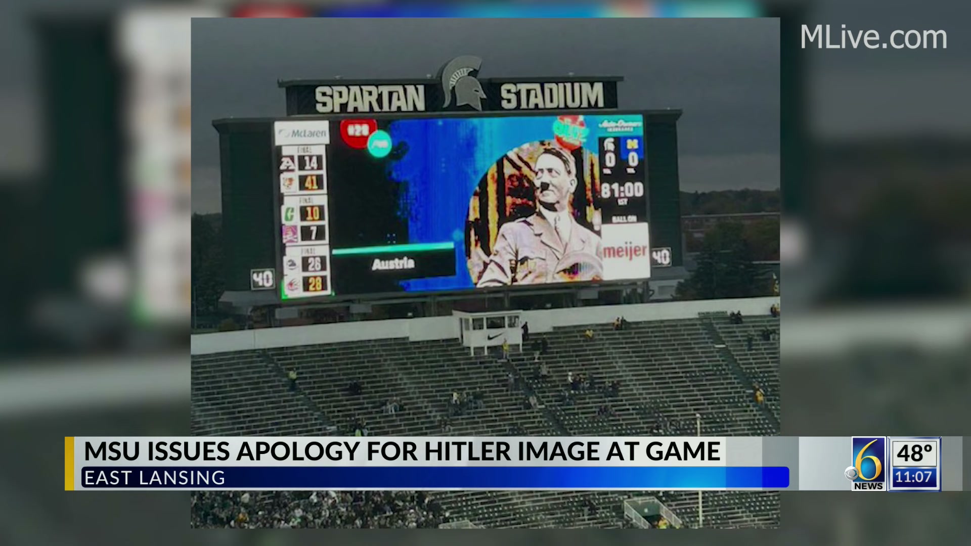An image of a jumbotron at Michigan State university before a football game. It has a giant photo of Hitler on it, as part of a trivia video.