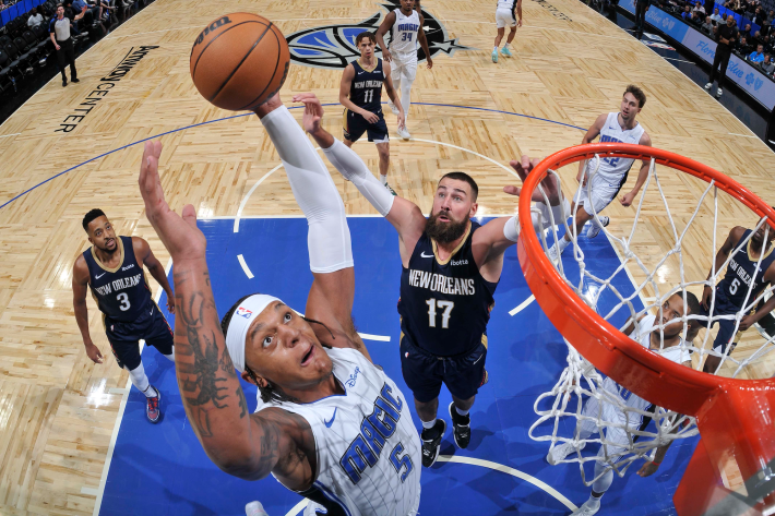 Paolo Banchero of the Orlando Magic leaps for a rebound against Jonas Valanciunas of the New Orleans Pelicans, in a preseason game.