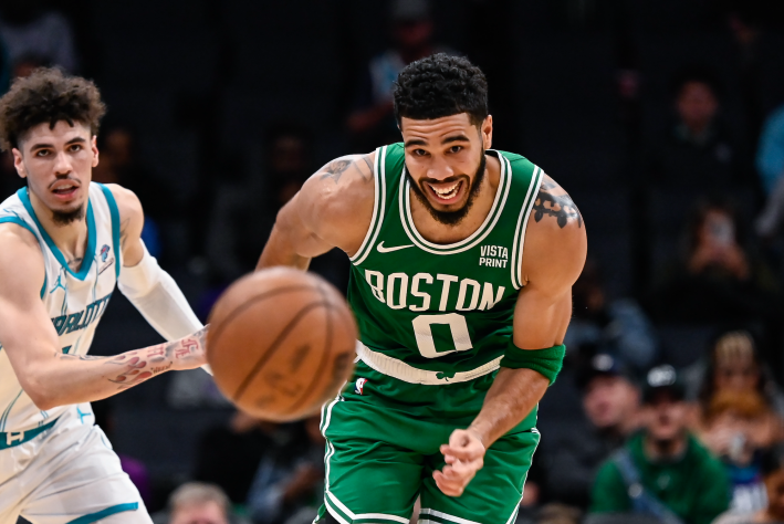 Jayson Tatum of the Boston Celtics races LaMelo Ball of the Charlotte Hornets for a loose ball.
