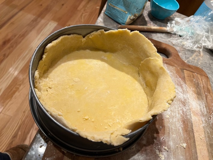 A beat-up and misshapen blob of dough inside a tart pan.