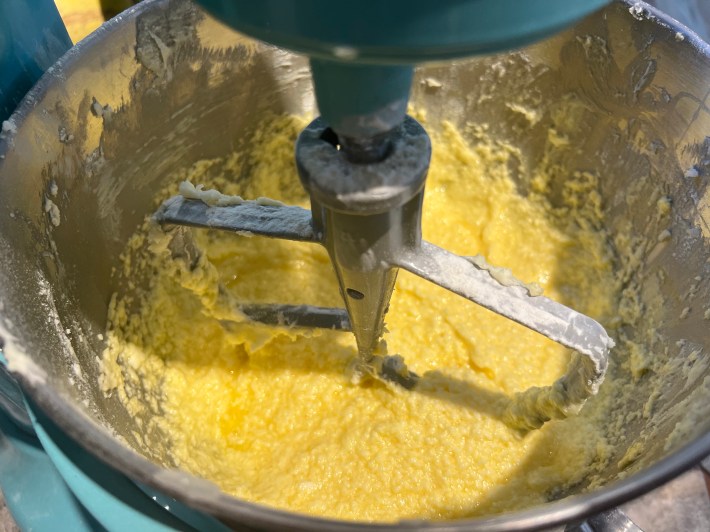 A stand mixer bowl holds a somewhat curdled mixture of butter, sugar, and egg.