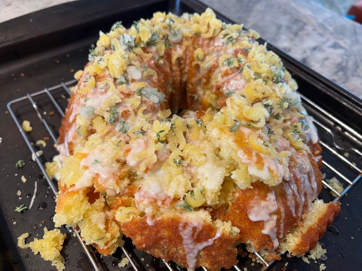 A crumbled and half-destroyed bundt cake, drizzled with icing and decorated with crystallized lemon peel and thyme.