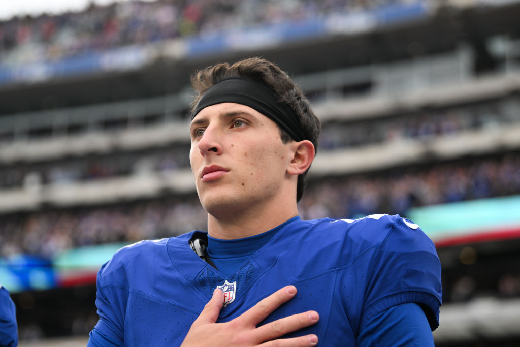 Tommy DeVito stands on the field with his hand over his heart