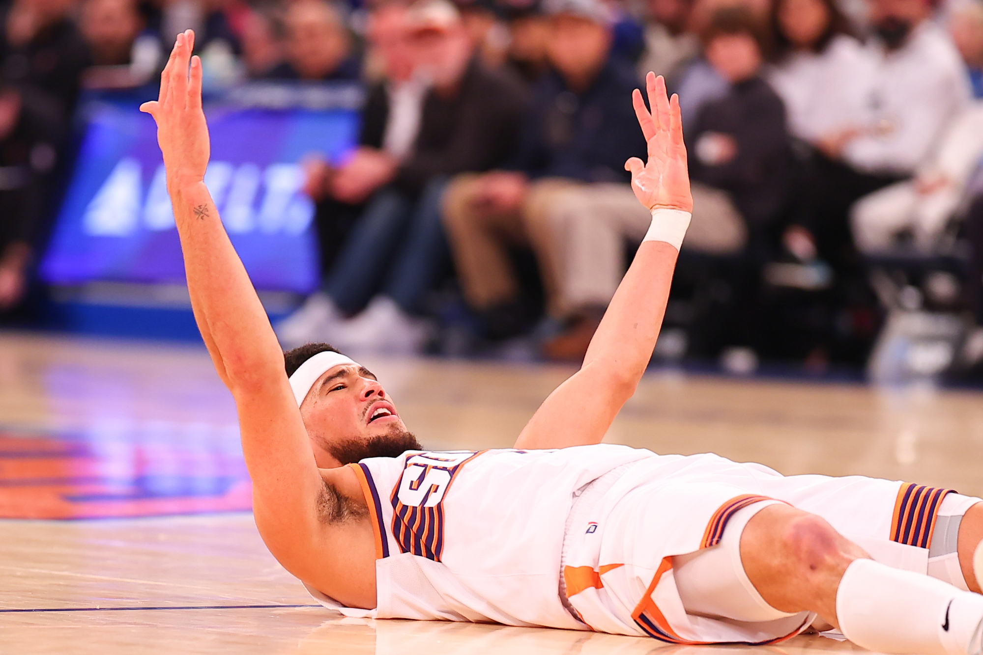 Devin Booker of the Suns celebrates on the floor against the Knicks