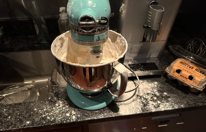 A kitchenaid stand mixer with flour exploded everywhere.