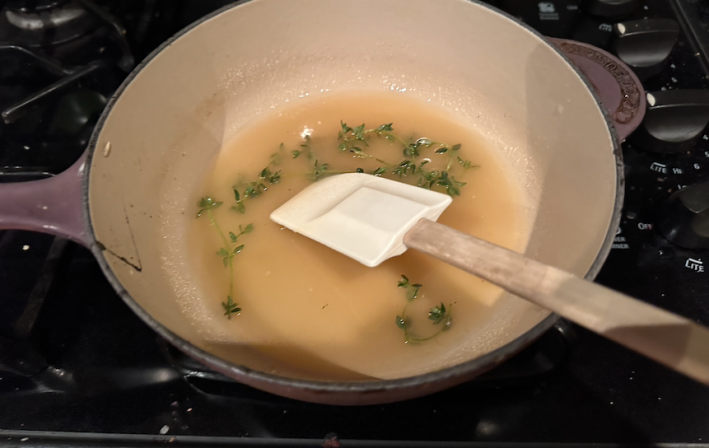 Thyme leaves inside simple syrup on the stove.