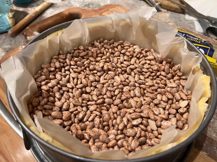 Trimmed dough lined with parchment and filled with dried beans.