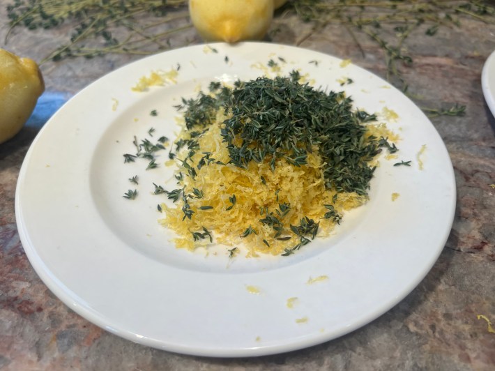 A large pile of lemon zest and thyme leaves on a small white plate.