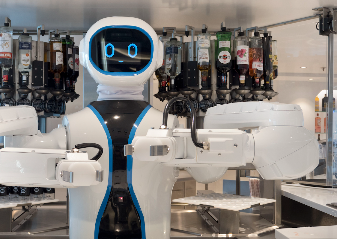 A goofy-looking robot bartender on a cruise ship, with a rack of various liquors behind it.