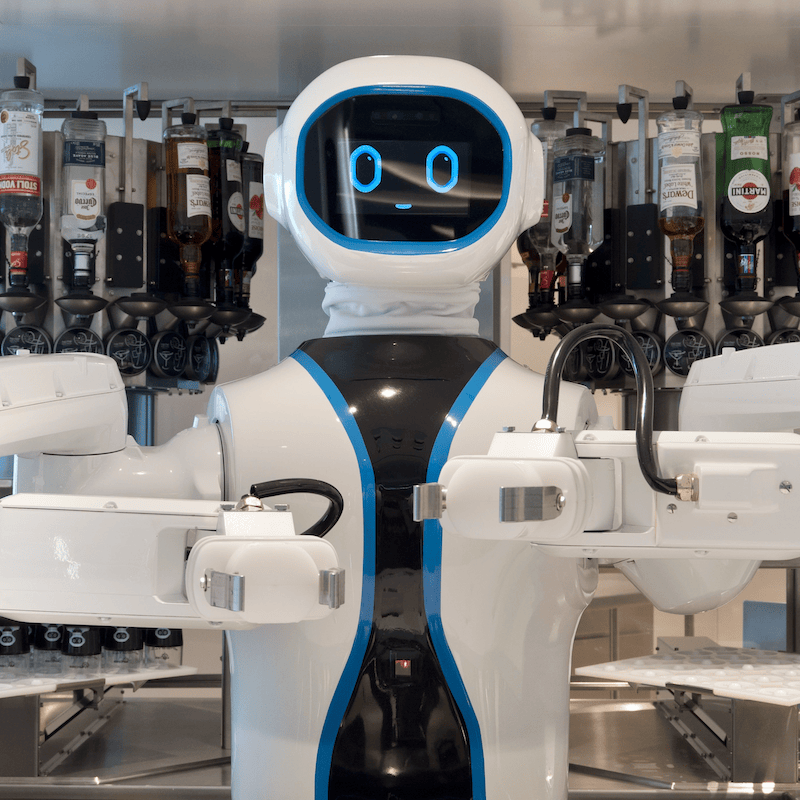 A goofy-looking robot bartender on a cruise ship, with a rack of various liquors behind it.