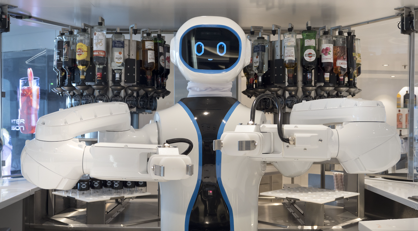 A goofy-looking robot bartender on a cruise ship, with a rack of various liquors behind it.