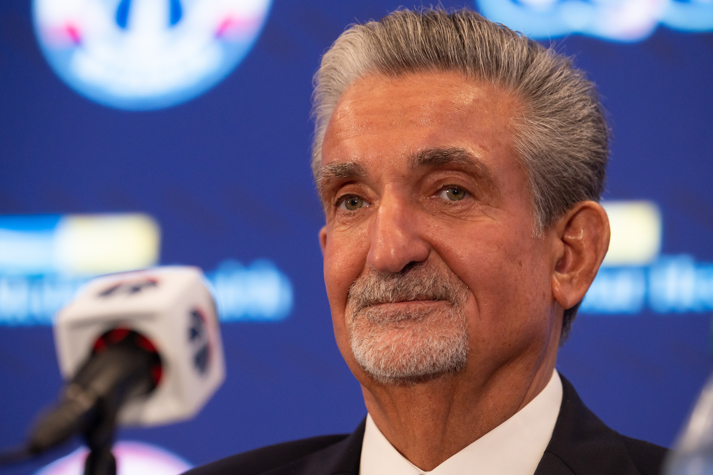 Ted Leonsis sits at a lectern emblazoned with Wizards logos.