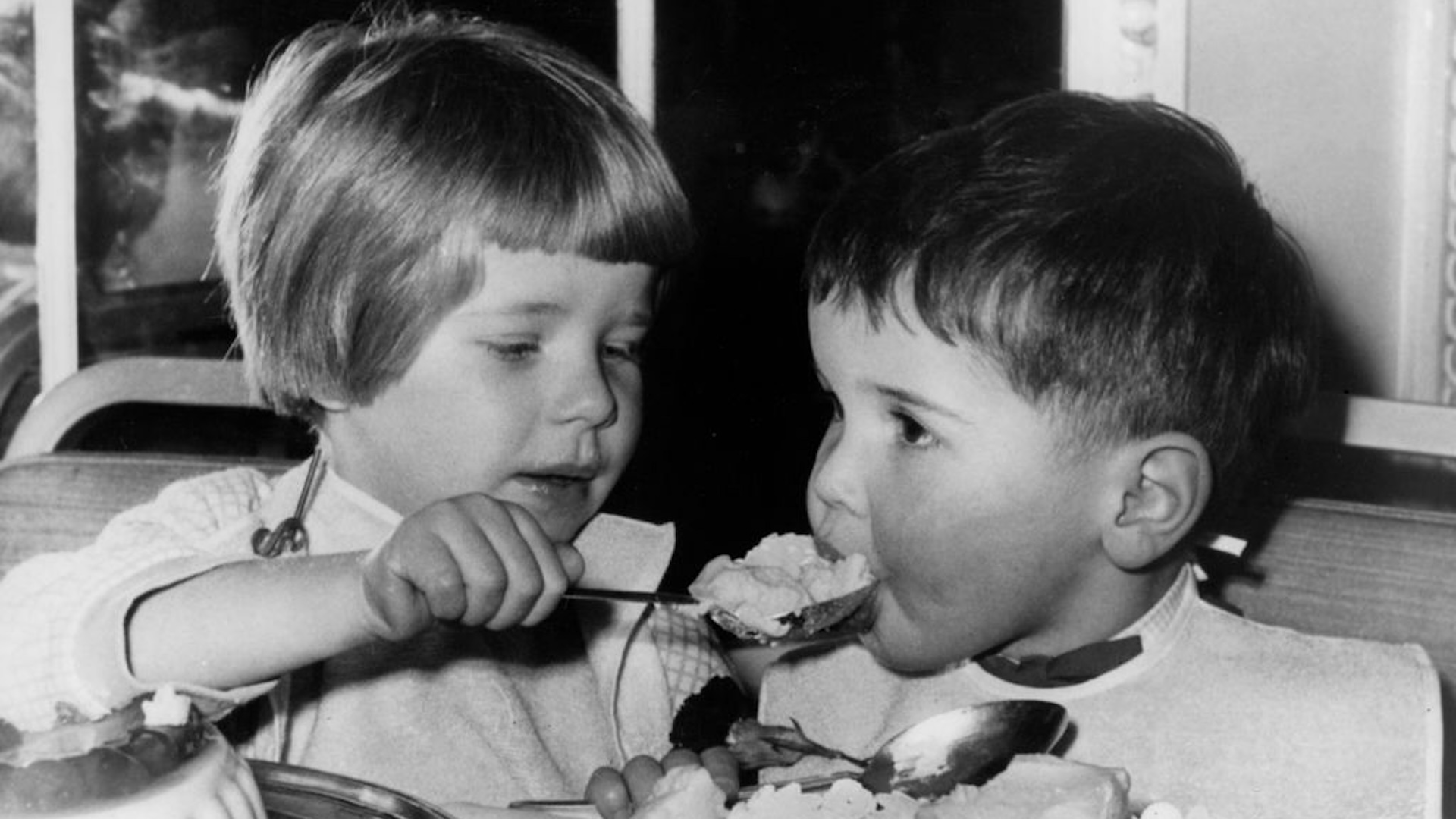 Two small children eating dessert.