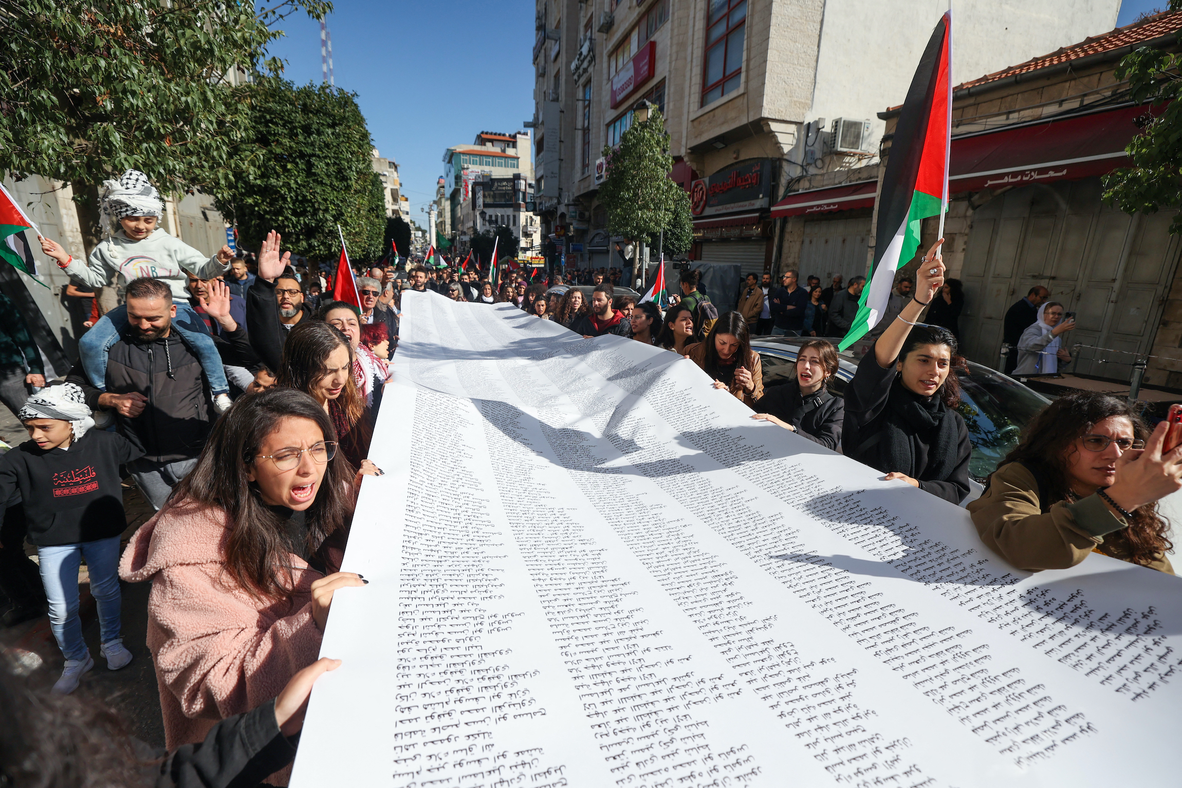 Palestinians carry a list of Gaza victims during a rally amid a general strike in the occupied West Bank.