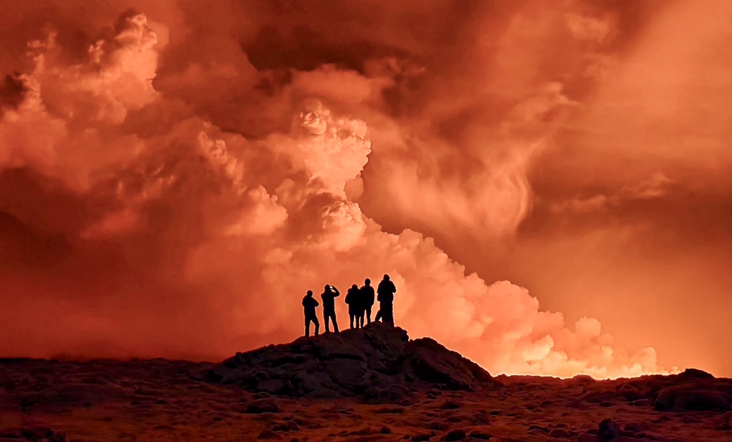 A crowd of Icelanders stands in awe of the volcanic cloud
