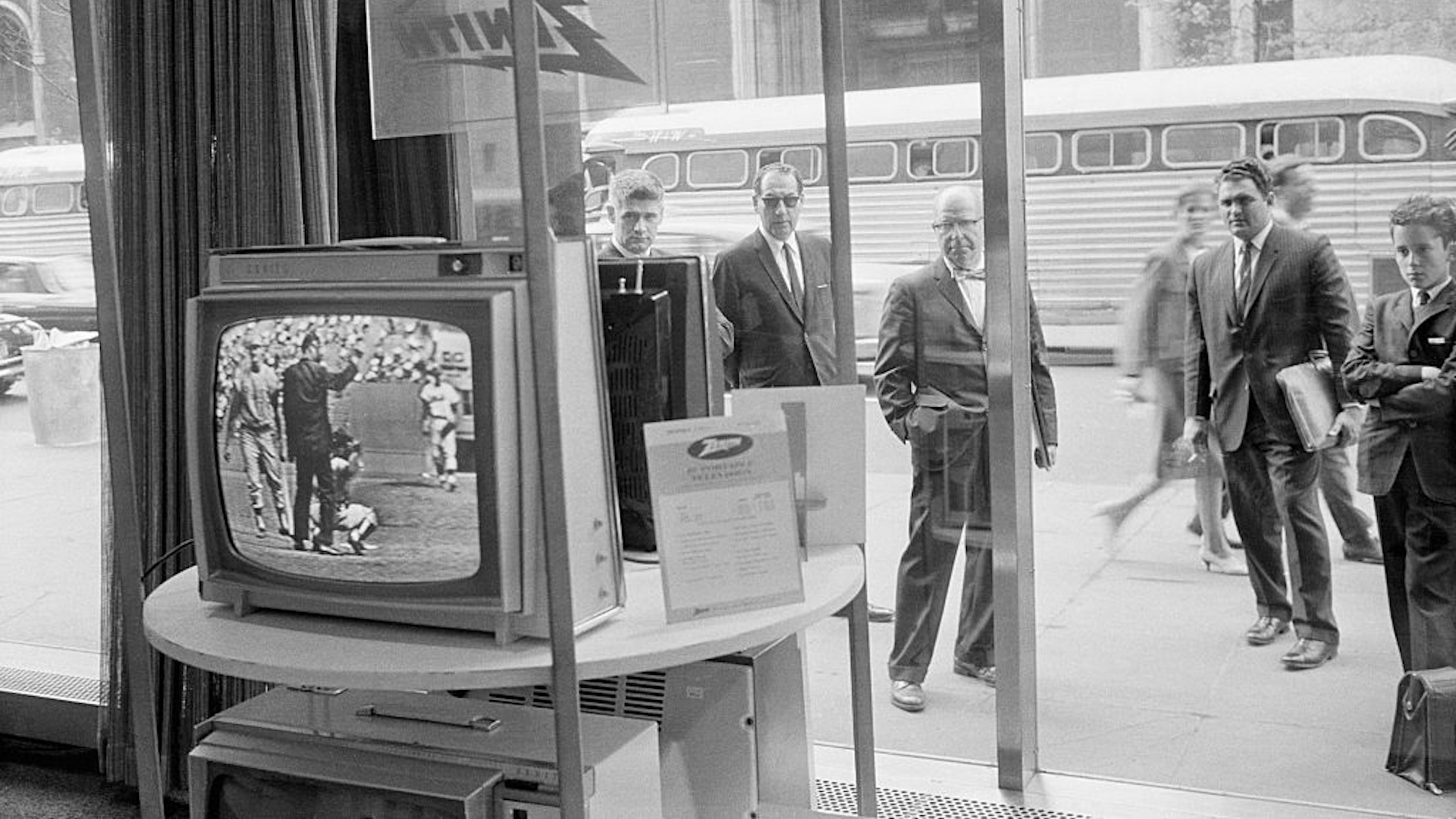 Businessmen stop outside the Zenith store window on Fifth Avenue to catch up on the televised New York Mets vs. Phillies baseball game. New York won 3 - 2. | Location: Fifth Avenue and 53rd Street, New York, New York, USA.