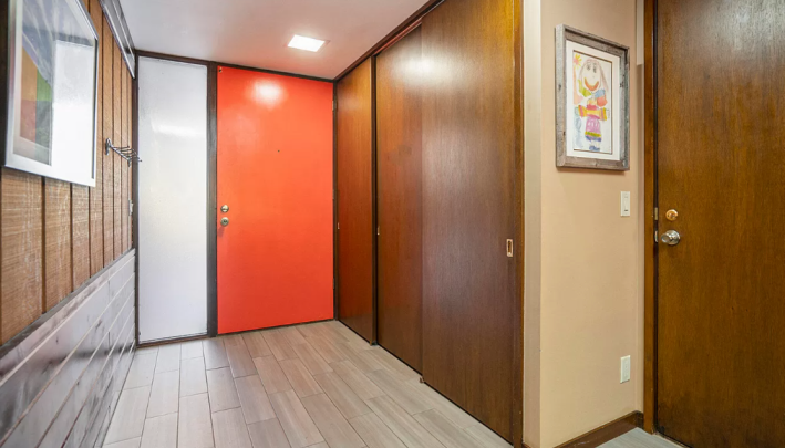 entryway with red door and framed children's art on the wall