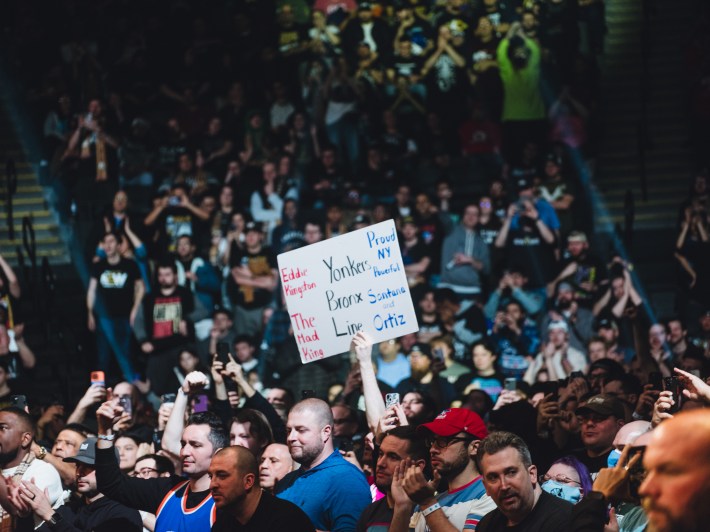 A fan at AEW Worlds End holds up a sign that reads: "Eddie Kingston, The mad King, Yonkers Bronx Line, Proud NY Powerful, Santana and Ortiz."