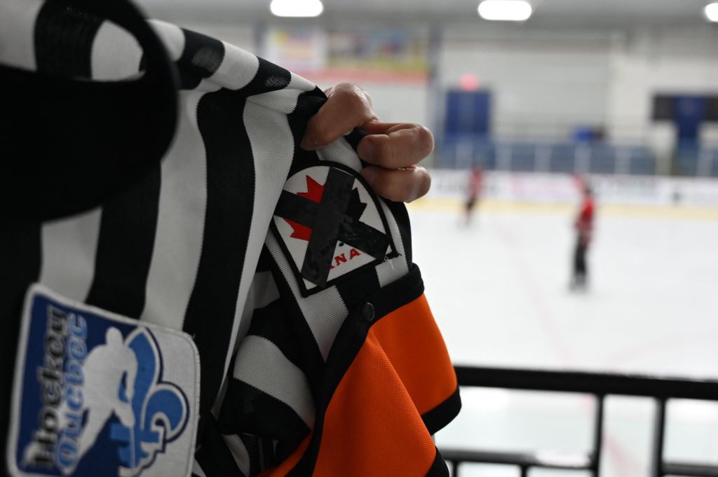 A referee wears a Hockey Canada patch crossed with black ribbon