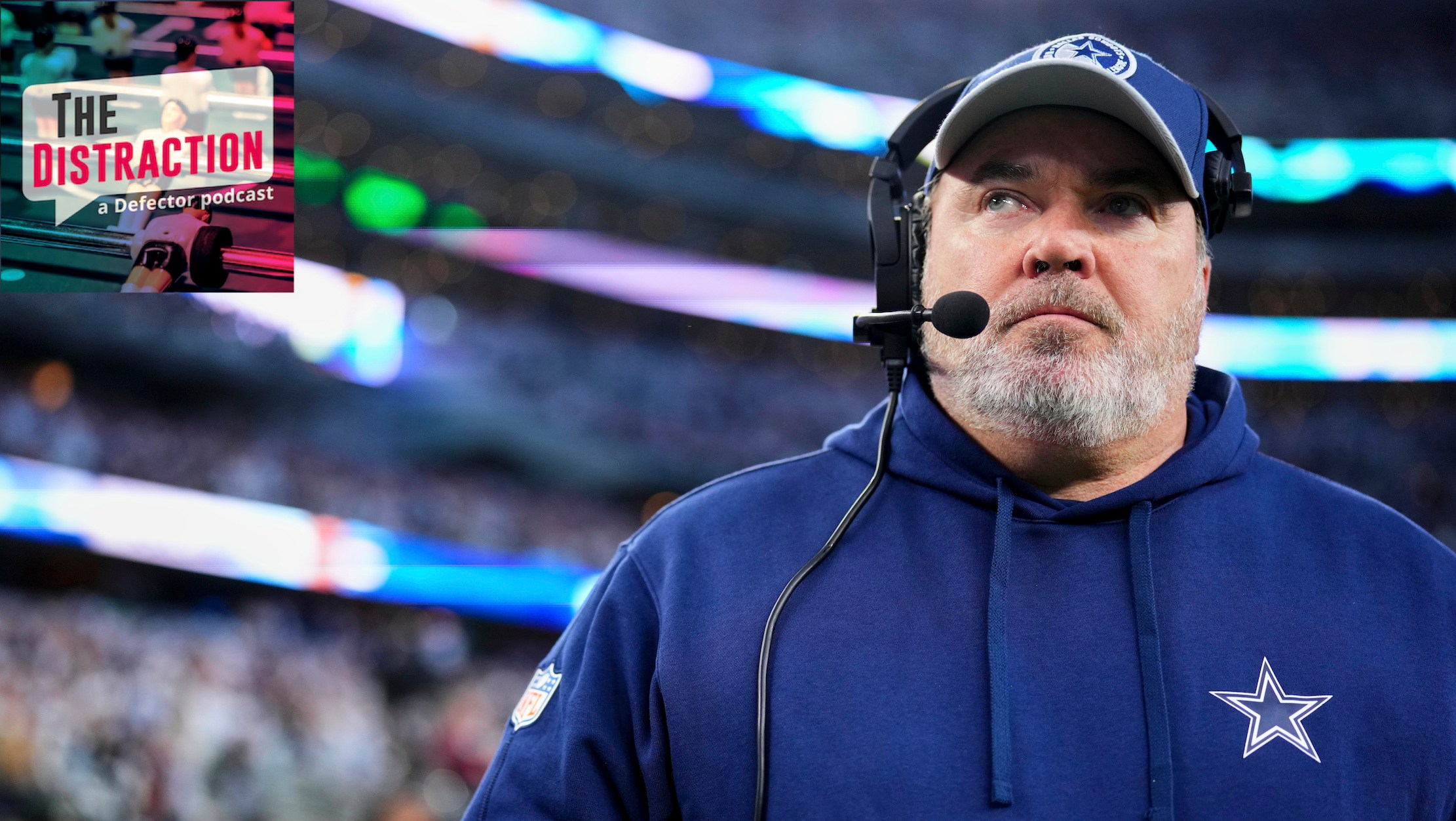 Dallas Cowboys coach Mike McCarthy seeming to look side-eyed at The Distraction logo at upper left, in a photo taken before the team's Wild Card loss to the Green Bay Packers.