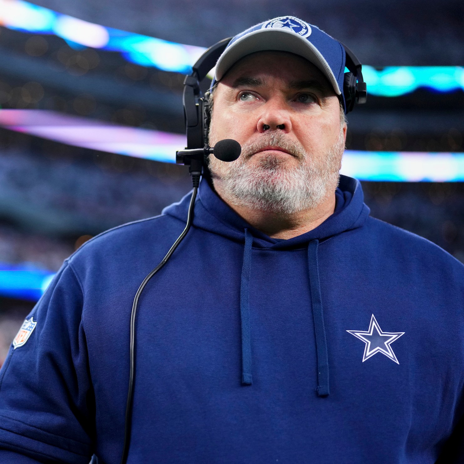 Dallas Cowboys coach Mike McCarthy seeming to look side-eyed at The Distraction logo at upper left, in a photo taken before the team's Wild Card loss to the Green Bay Packers.