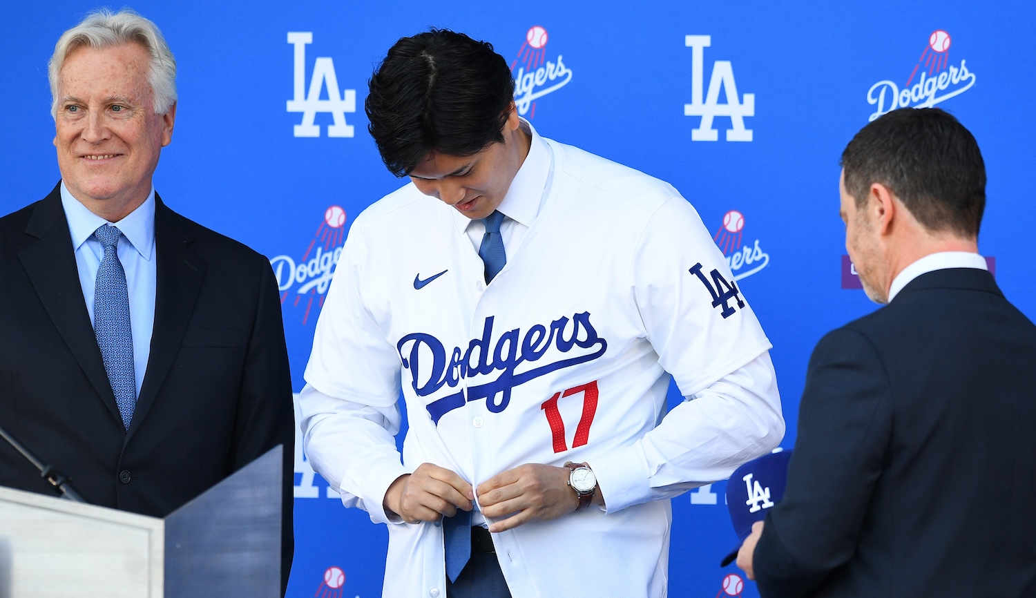 Newly acquired Los Angeles Dodgers designated hitter Shohei Ohtani puts on his jersey for the first time as Chairman of the Los Angeles Dodgers Mark Walter looks on during a press conference on December 14, 2023 at Dodger Stadium in Los Angeles, CA. (Photo by Brian Rothmuller/Icon Sportswire via Getty Images)