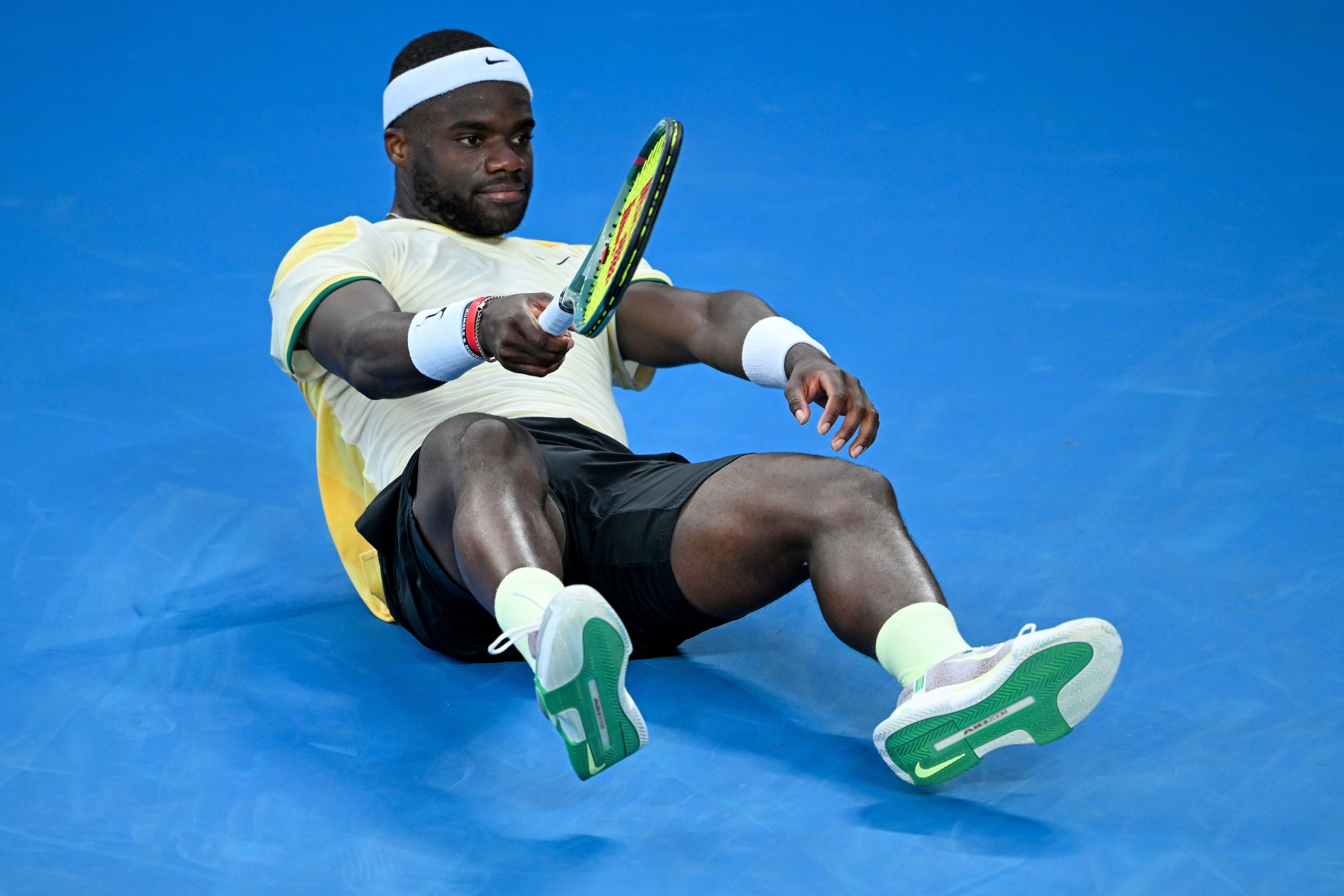 MELBOURNE, AUSTRALIA - JANUARY 17: Frances Tiafoe of the United States falls to ground in the round two men's singles match against Tomas Machac of the Czech Republic during the 2024 Australian Open at Melbourne Park on January 17, 2024 in Melbourne, Australia. (Photo by Will Murray/Getty Images)