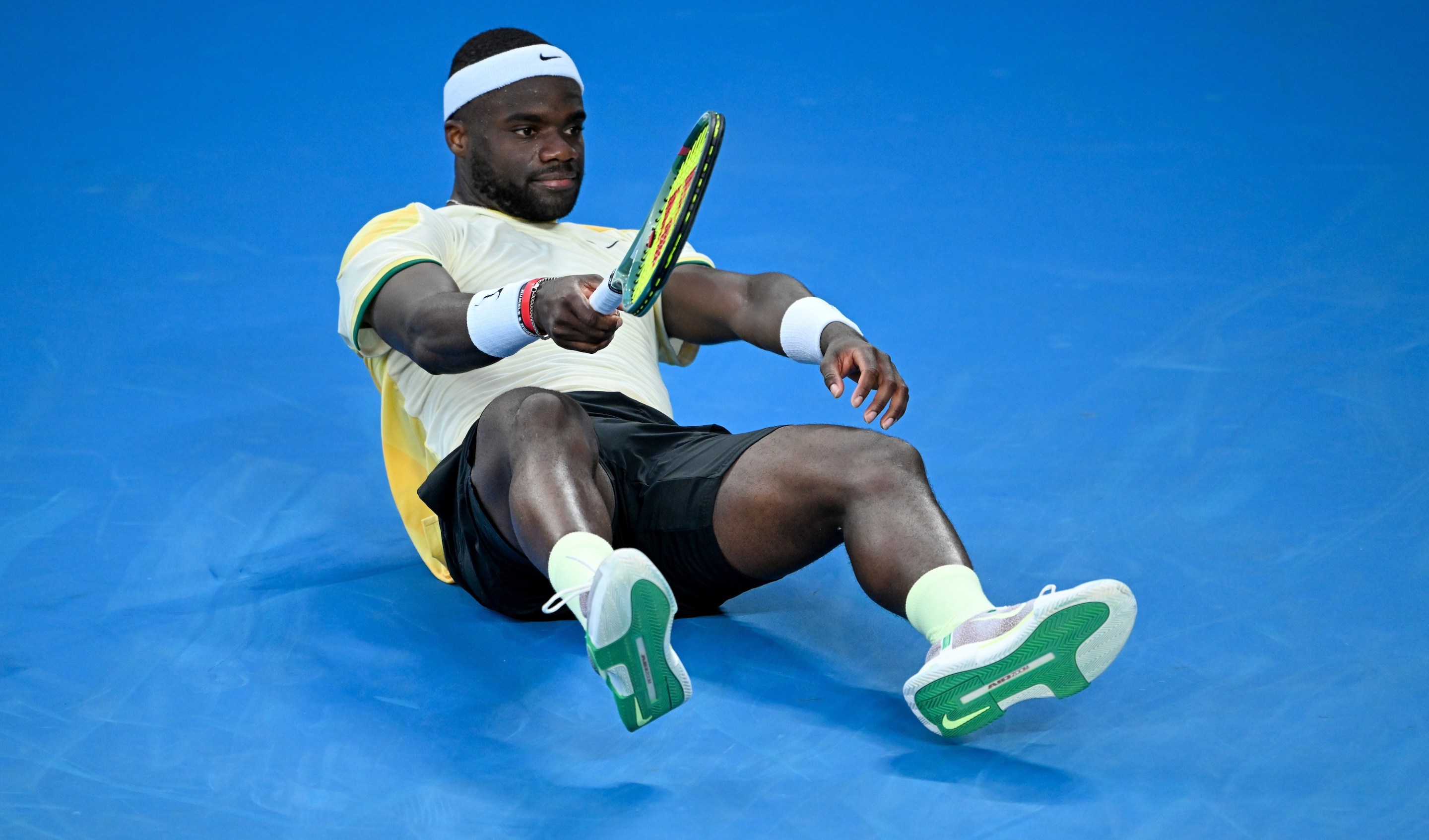 MELBOURNE, AUSTRALIA - JANUARY 17: Frances Tiafoe of the United States falls to ground in the round two men's singles match against Tomas Machac of the Czech Republic during the 2024 Australian Open at Melbourne Park on January 17, 2024 in Melbourne, Australia. (Photo by Will Murray/Getty Images)
