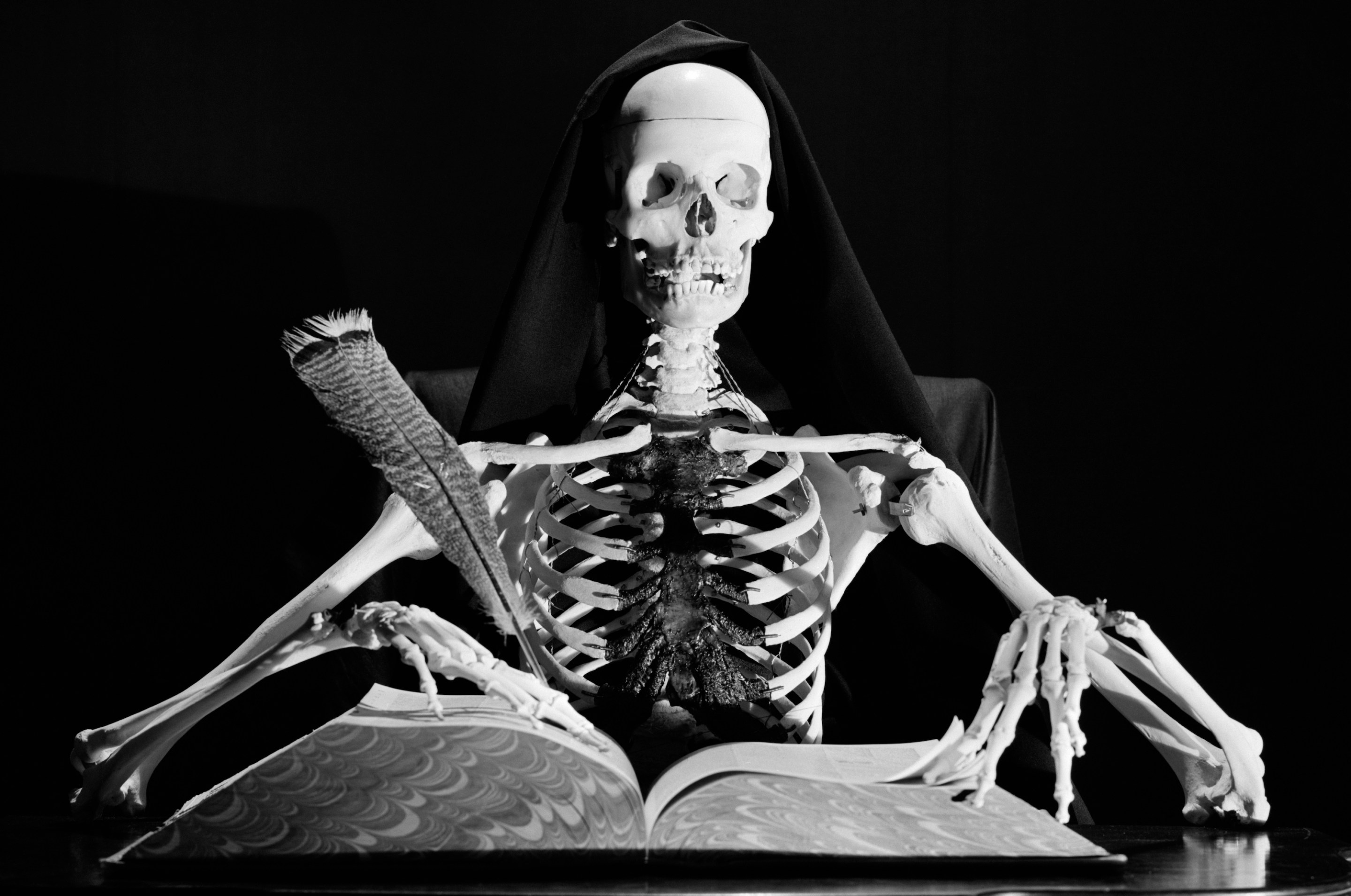 STILL LIFE OF SKELETON WRITING IN LARGE BOOK WITH QUILL PEN (Photo by H. Armstrong Roberts/ClassicStock/Getty Images)