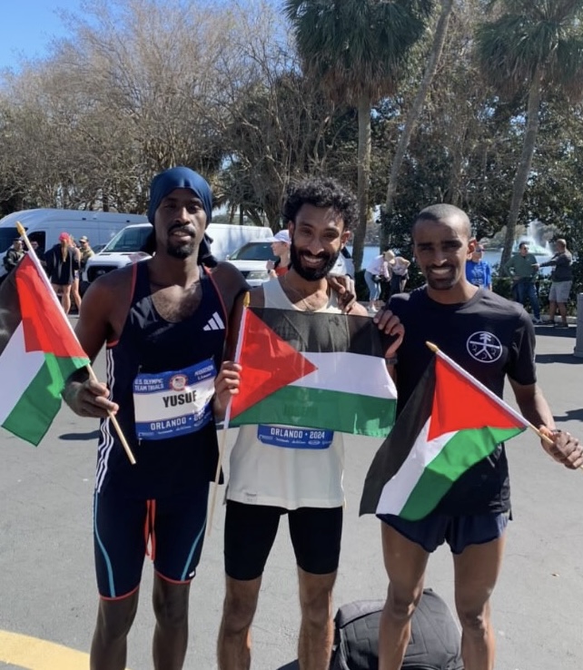 Three runners posing for photo with Palestinian flags