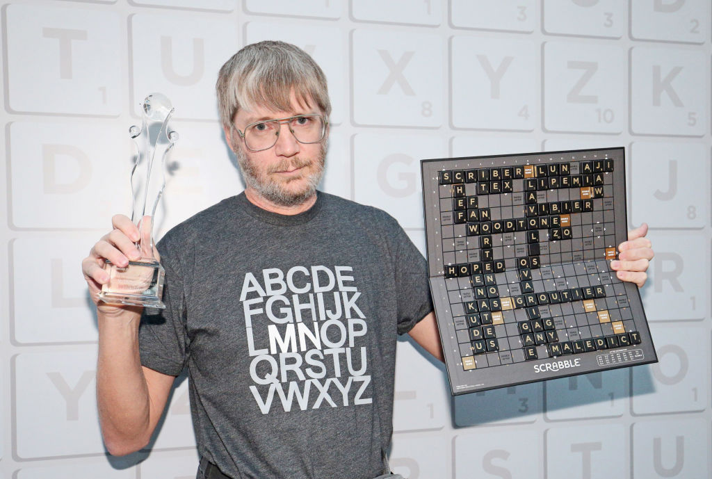 Scrabble World Champion Nigel Richards holds up a trophy and shows the final winning board in London in 2018