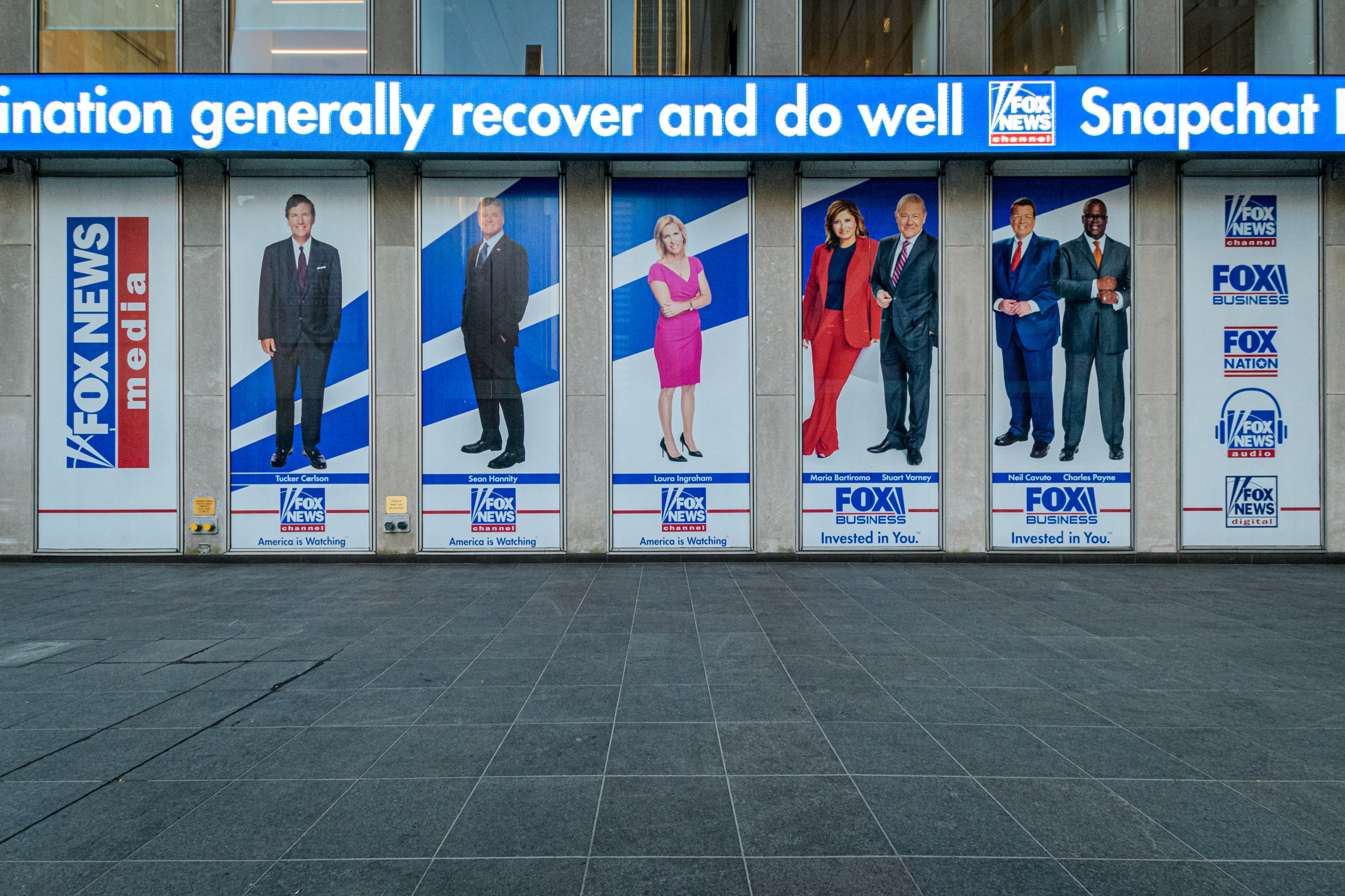 Giant portraits of the news anchors at Fox News headquarters building in New York City. Very cursed image.