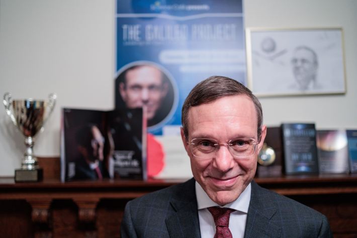 the astrophysicist Avi Loeb smiling in front of various paraphernalia of his face