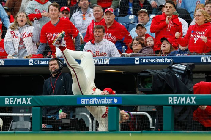 PHILADELPHIA, PENNSYLVANIA - MARCH 30: First baseman Bryce Harper #3 of the Philadelphia Phillies chases a foul ball hit by Austin Riley #27 of the Atlanta Braves and flips over the dugout railing during the first inning of a game at Citizens Bank Park on March 30, 2024 in Philadelphia, Pennsylvania.