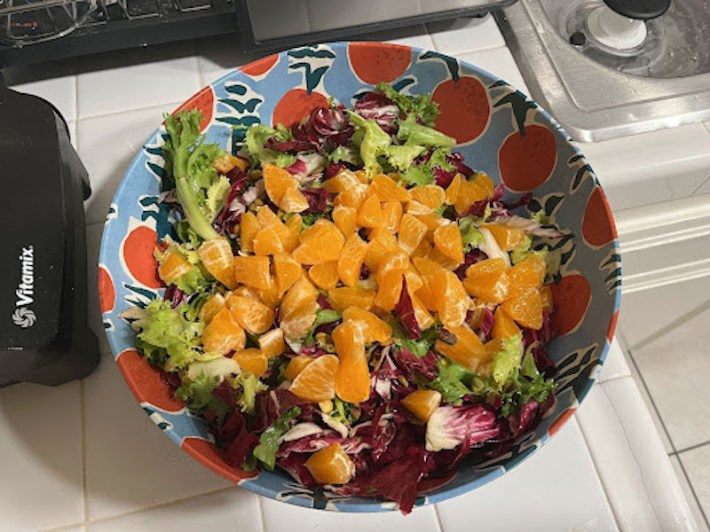 A big bowl with salad greens, radicchio, and sliced oranges in it.