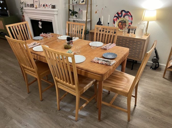The same wood table, now fully set with plates, napkins, utensils, and glasses.