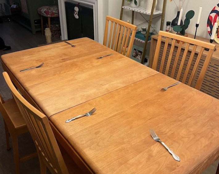 A nice wood table with place settings that are, for now, just forks.