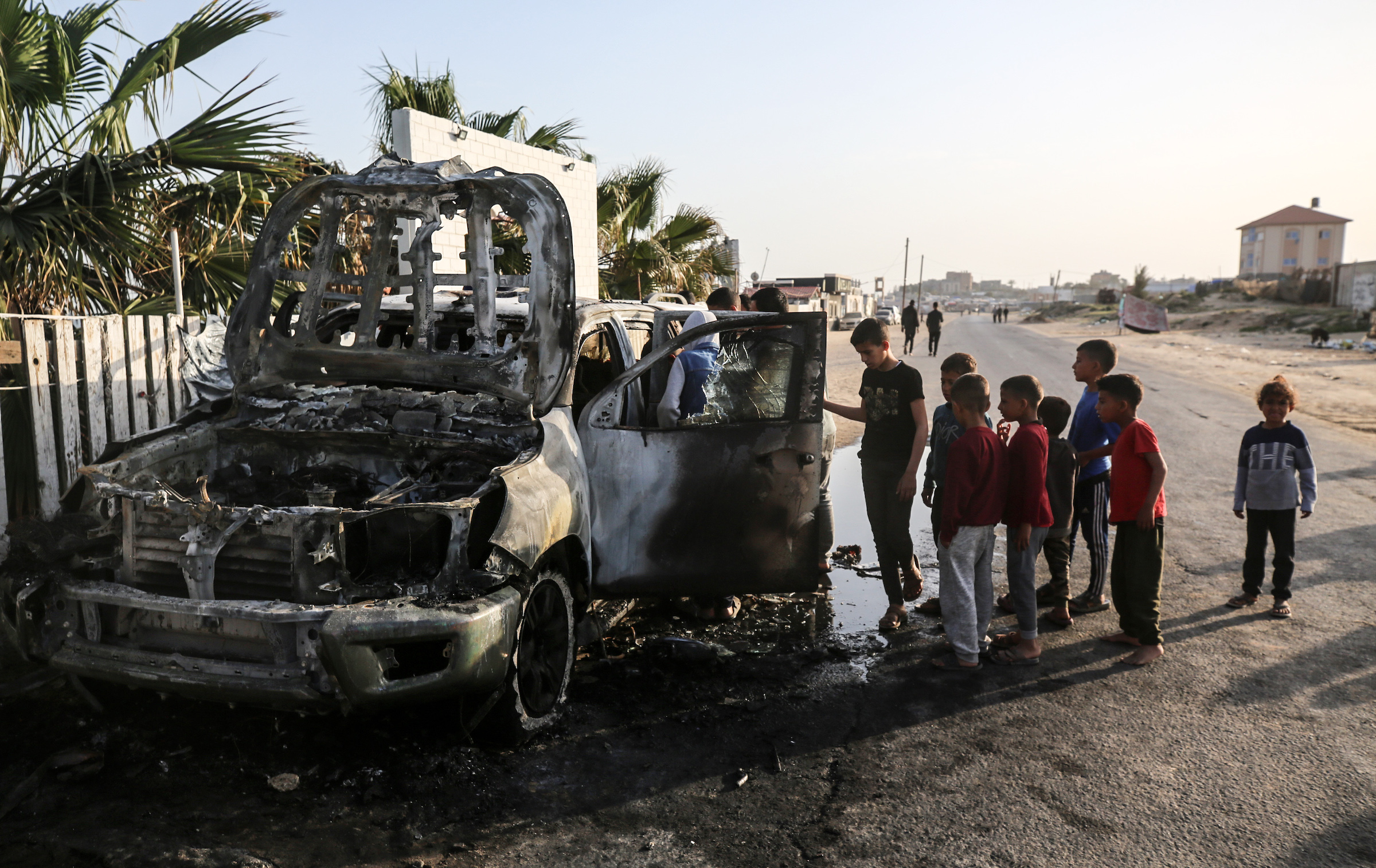 Palestinian children are standing next to a bombed-out WCK vehicle in Deir Al-Balah, in the central Gaza Strip.