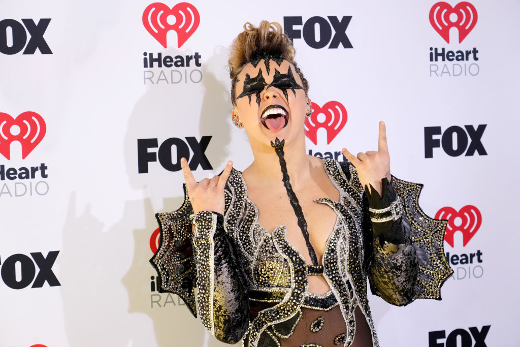 Singer JoJo Siwa on the red carpet entering the 2024 iHeartRadio Music Awards in Hollywood, wearing a black and silver sequins outfit reminiscent of Gene Simmons from the band Kiss.